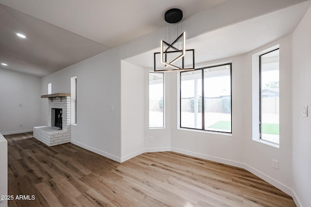 unfurnished living room featuring wood-type flooring, a fireplace, and an inviting chandelier