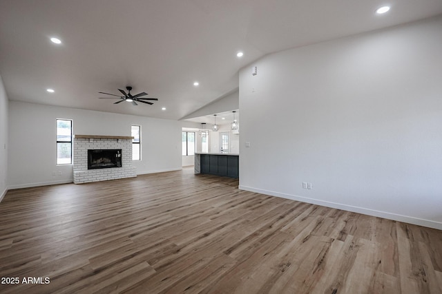 unfurnished living room featuring a fireplace, ceiling fan, plenty of natural light, and hardwood / wood-style flooring