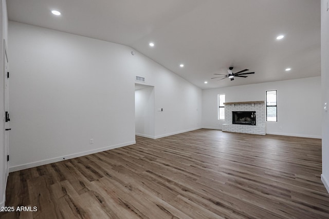 unfurnished living room featuring ceiling fan, wood-type flooring, a fireplace, and vaulted ceiling