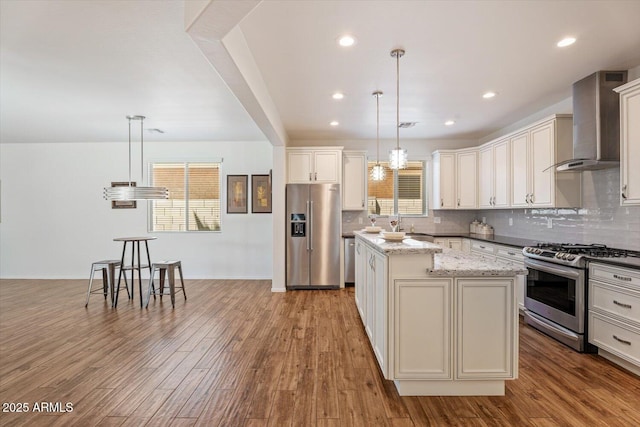 10417 W Alyssa Ln, Peoria, AZ 85383 - kitchen featuring wall chimney exhaust hood, wood finished floors, stainless steel appliances, decorative backsplash, and a kitchen island