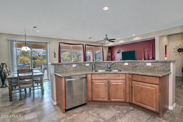 kitchen featuring light stone countertops, sink, stainless steel dishwasher, and pendant lighting