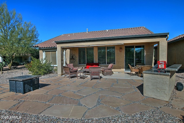 back of property featuring a patio area and an outdoor living space with a fire pit