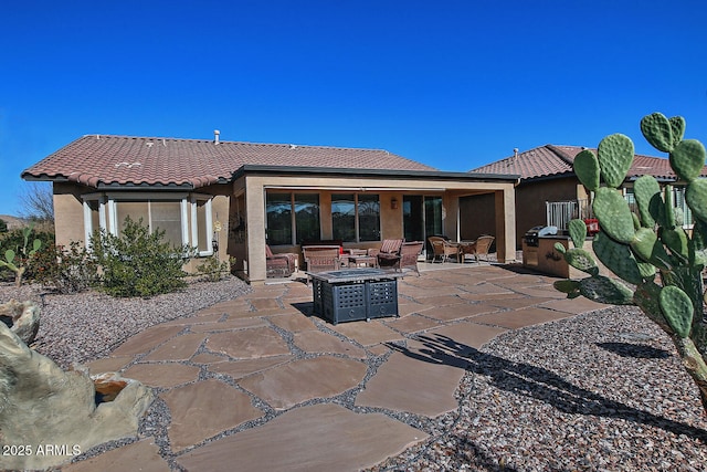 rear view of property featuring a patio, exterior kitchen, and a fire pit