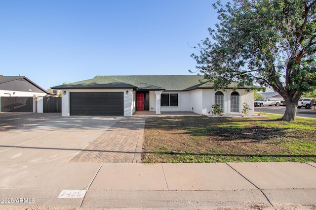single story home with fence, an attached garage, a front lawn, stucco siding, and concrete driveway
