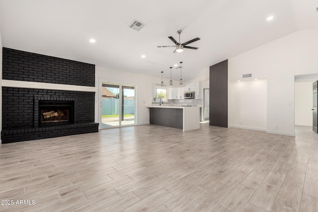 unfurnished living room with visible vents, a ceiling fan, high vaulted ceiling, and light wood-type flooring