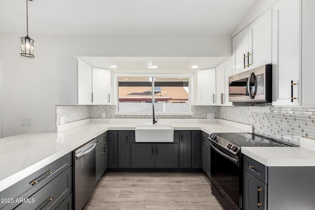 kitchen featuring appliances with stainless steel finishes, light stone counters, a sink, white cabinetry, and backsplash