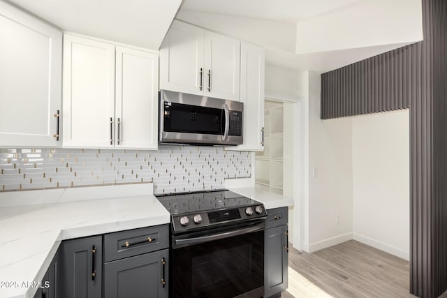 kitchen featuring white cabinets, stainless steel appliances, light stone countertops, and decorative backsplash