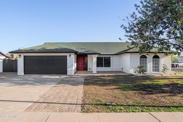 ranch-style house with an attached garage, driveway, a shingled roof, and stucco siding