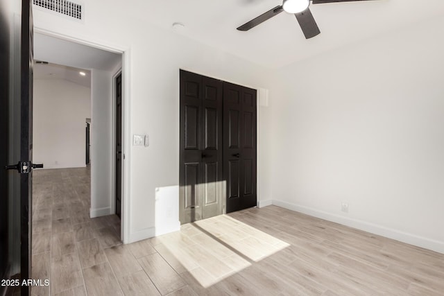 unfurnished bedroom with visible vents, light wood-style flooring, baseboards, and a closet