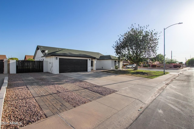 single story home with a gate, fence, concrete driveway, an attached garage, and stucco siding