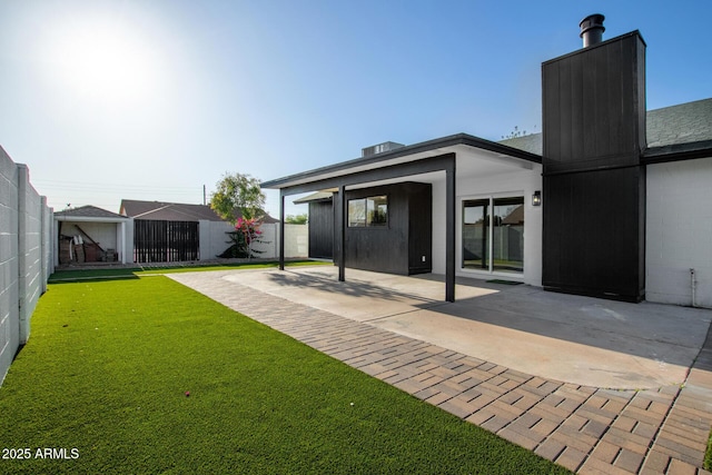 back of property with a yard, a patio, fence, and a chimney