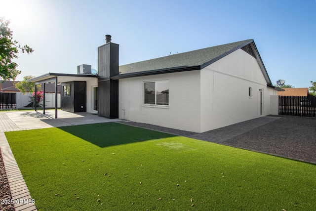 back of house featuring a chimney, a lawn, fence, cooling unit, and a patio