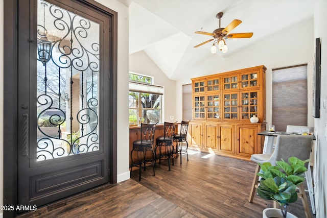 entryway featuring lofted ceiling, ceiling fan, dark wood-type flooring, baseboards, and a dry bar