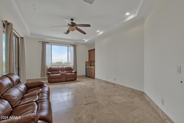 tiled living room featuring a raised ceiling and ceiling fan