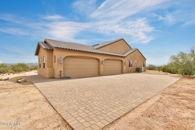 mediterranean / spanish-style house with central AC unit and a garage