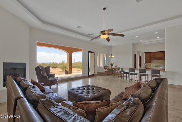 living room with ceiling fan and a tray ceiling