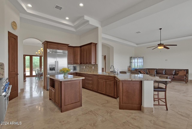 kitchen featuring ceiling fan with notable chandelier, light tile floors, tasteful backsplash, and light stone countertops