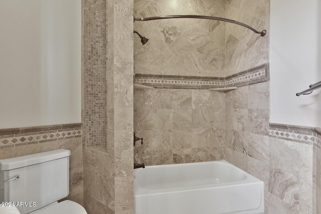 bathroom featuring tile walls, toilet, and tiled shower / bath