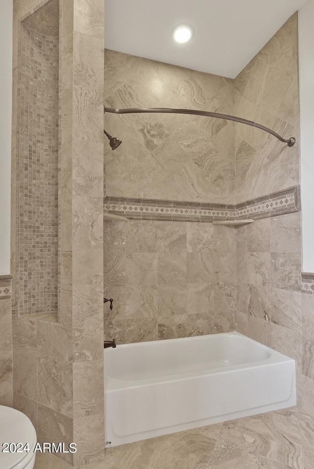 bathroom with tile walls, toilet, tiled shower / bath, and tile flooring