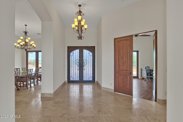 entryway featuring light tile floors, french doors, and ceiling fan with notable chandelier