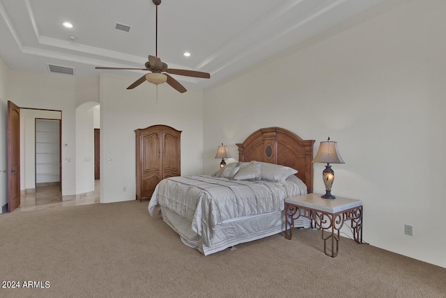 carpeted bedroom featuring ceiling fan, a high ceiling, and a raised ceiling