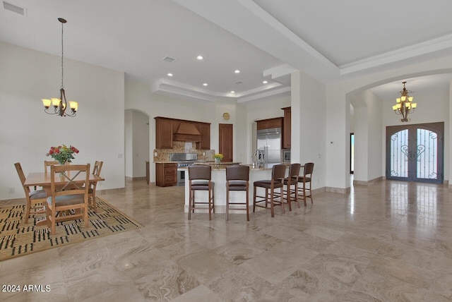 tiled dining room featuring a chandelier, a tray ceiling, french doors, and a towering ceiling