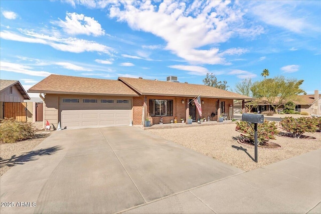 ranch-style house featuring concrete driveway, brick siding, fence, and an attached garage