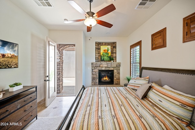 bedroom with a stone fireplace and ceiling fan