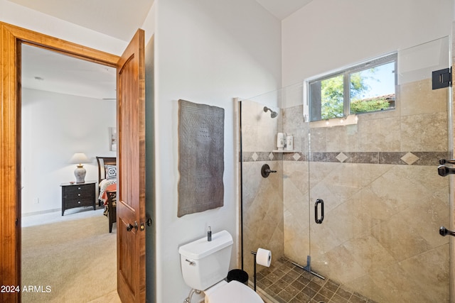 bathroom featuring a shower with door and toilet