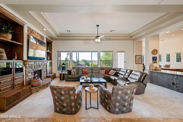 living room with ceiling fan, a raised ceiling, a fireplace, and light tile patterned floors