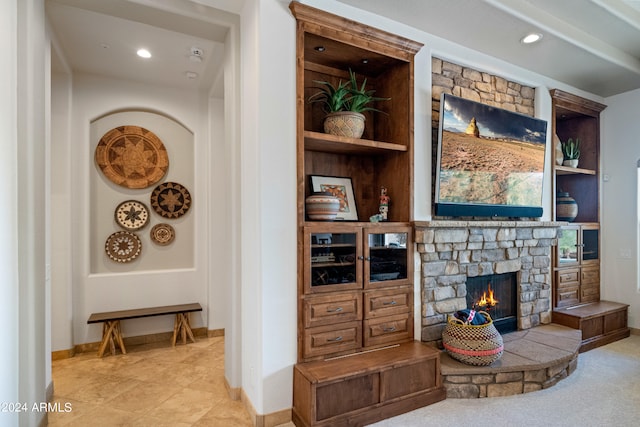 living room with built in shelves, a stone fireplace, and light tile patterned flooring