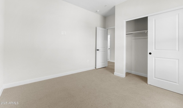 unfurnished bedroom with light carpet, a closet, and baseboards
