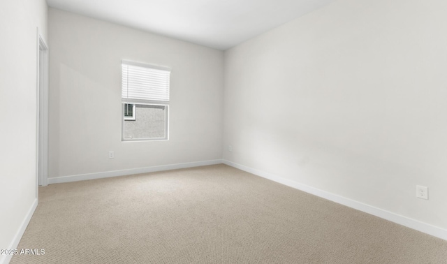 empty room featuring baseboards and light carpet