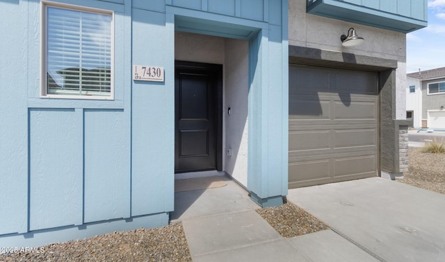 entrance to property featuring driveway, a garage, and board and batten siding