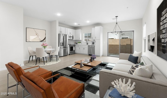 living area with a chandelier, light wood-style flooring, baseboards, and recessed lighting