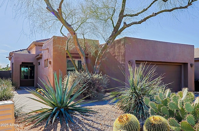 adobe home featuring a garage and stucco siding