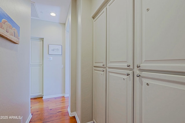 hall featuring visible vents, baseboards, and light wood-style floors