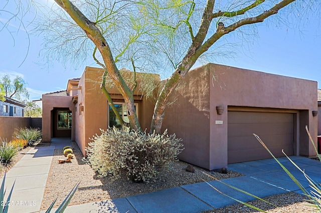 pueblo-style home featuring stucco siding, driveway, and an attached garage