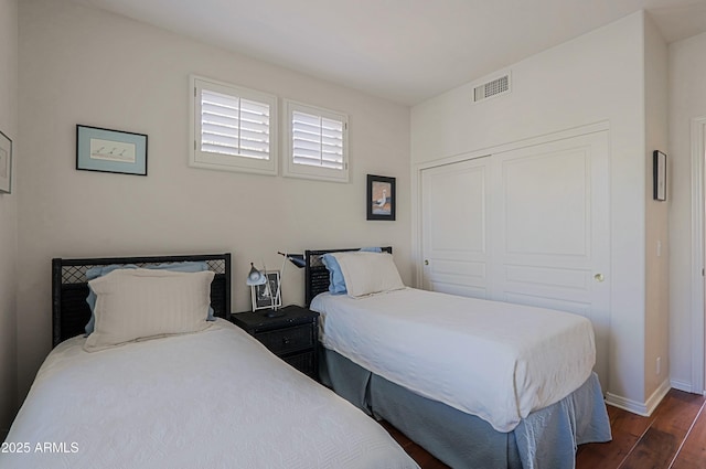 bedroom featuring dark wood finished floors, baseboards, visible vents, and a closet