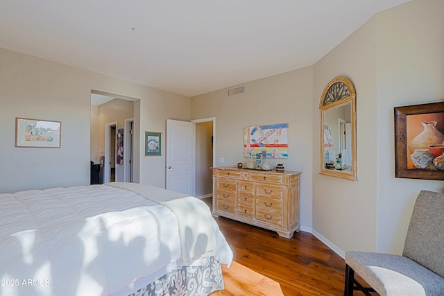 bedroom featuring visible vents, baseboards, and wood finished floors