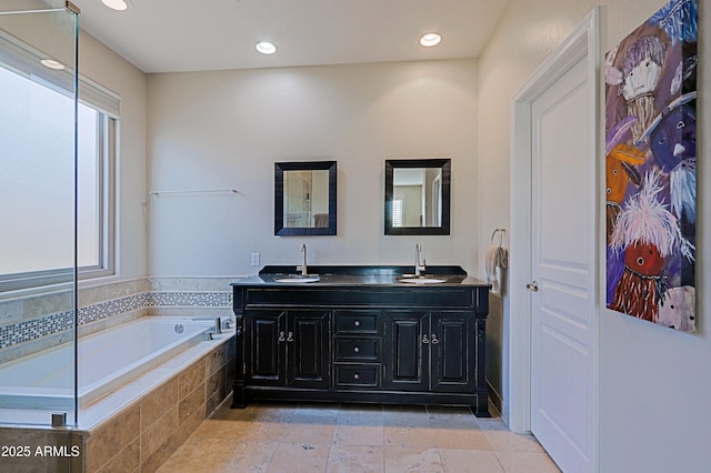 full bathroom with double vanity, a bath, recessed lighting, and a sink