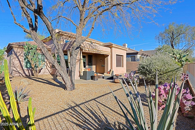 rear view of property with an outdoor living space, fence, stucco siding, a chimney, and a patio area