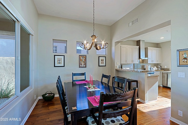 dining room featuring a chandelier, visible vents, baseboards, and wood finished floors