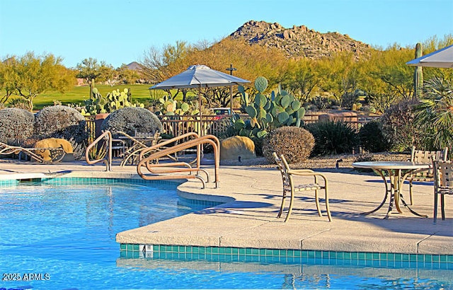 pool with a patio area and a mountain view