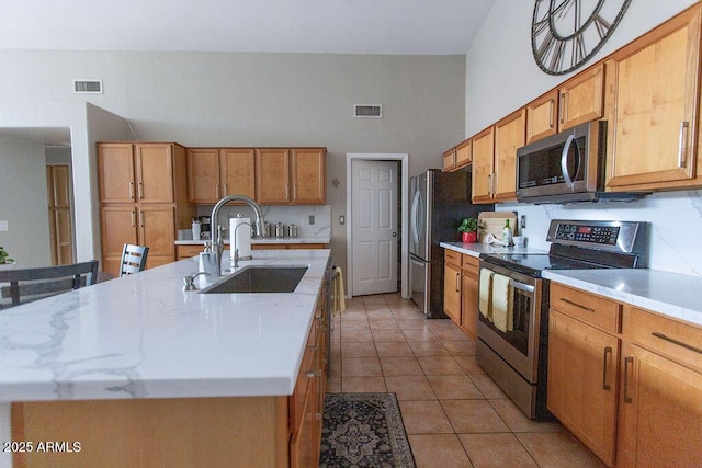 1894 E Sagebrush St, Gilbert, AZ 85296 - kitchen with stainless steel appliances, a sink, brown cabinets, light tile patterned floors, and a towering ceiling