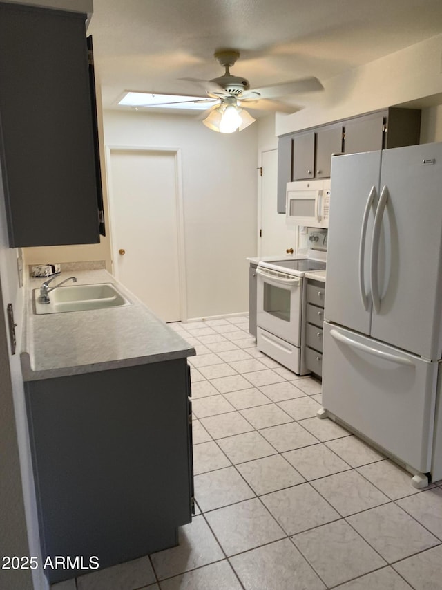 kitchen featuring light tile patterned floors, white appliances, a ceiling fan, and a sink