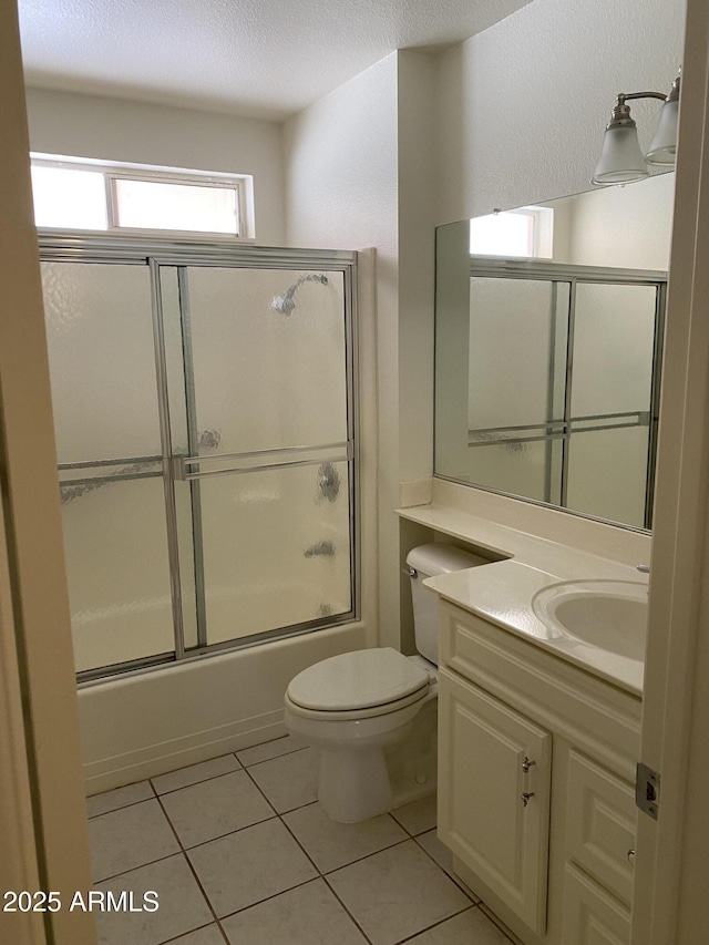 full bathroom featuring toilet, a textured ceiling, tile patterned flooring, bath / shower combo with glass door, and vanity