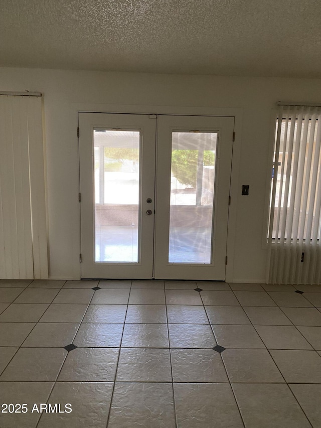 doorway to outside featuring french doors, a textured ceiling, and light tile patterned flooring