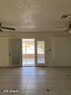 empty room with visible vents, a textured ceiling, and a ceiling fan