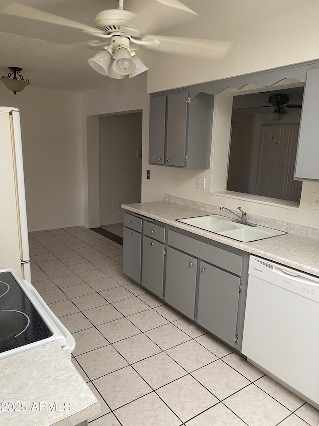 kitchen with gray cabinetry, a sink, white appliances, light tile patterned flooring, and ceiling fan